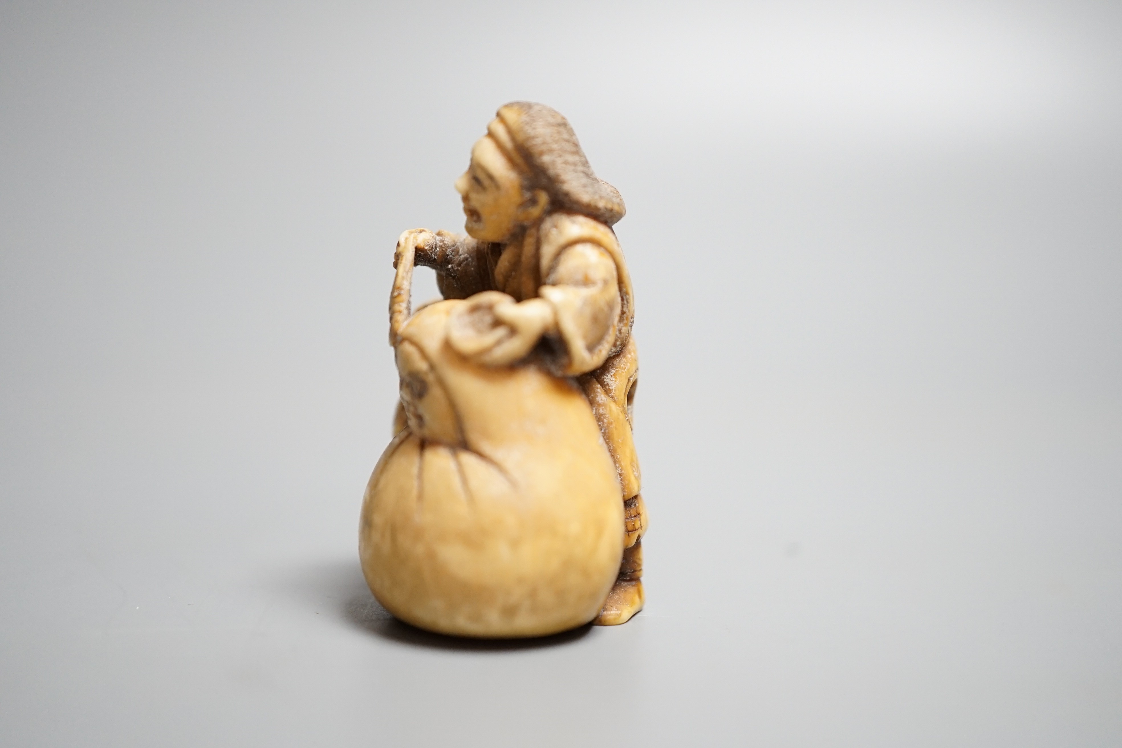 A Japanese ivory netsuke of an artisan and apprentice painting a Daruma doll, early 20th century,height 4cm